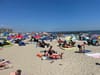 Hundreds of beachgoers sit on blankets on a brilliant summer day in the Rockaways.