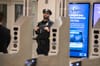 An NYPD officer stands watch outside a subway turnstile.