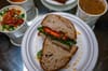 A vegan sandwich called The Gunther sits on a plate surrounded by various soups.