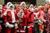 A group of revelers at SantaCon laugh at something on the street.