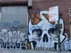 A parking sign in front of a skull mural