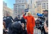 Someone in an orange jumpsuit and a Donald Trump mask demonstrating outside of the Manhattan Criminal Courthouse on the day o