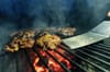 A close-up of a bunch of hamburger patties on a charcoal grill.