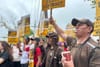 A group of people, many UPS workers in brown uniforms, hold signs saying "Just Practicing for a Just Contract"