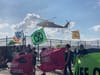 Protesters' banners flap in the prop-wash of a helicopter.