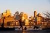 A woman walks her dogs along South Street with a view towards the Brooklyn waterfront.