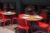 A group of red chairs sitting around a wooden table at a restaurant in New York City.